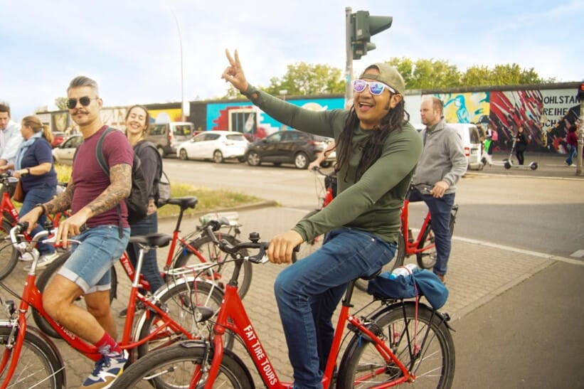 A group of cyclists enjoy themselves in front of the East Side Gallery in Berlin, Germany