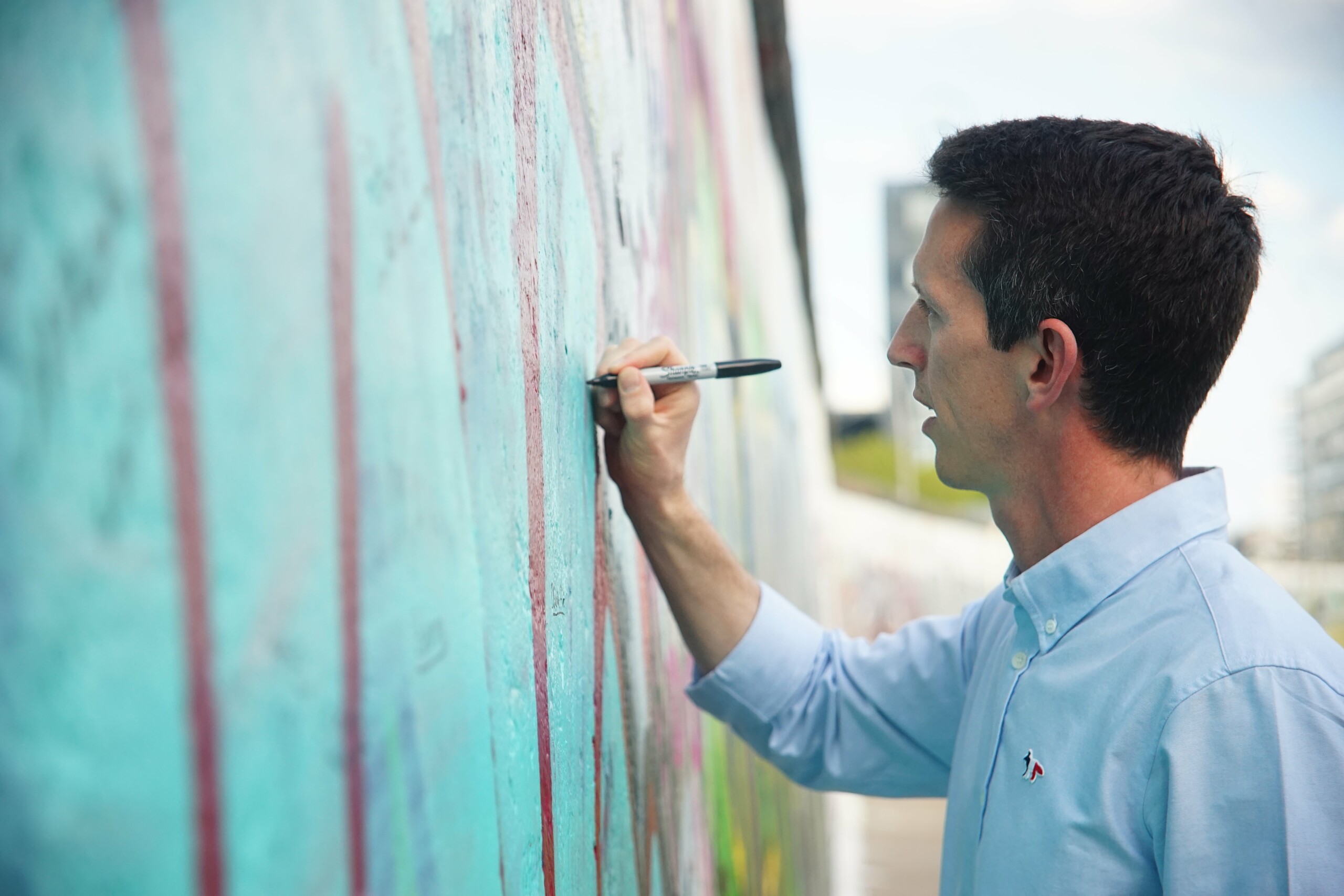 A man writes on the Berlin Wall at the East Side Gallery in Berlin, Germany