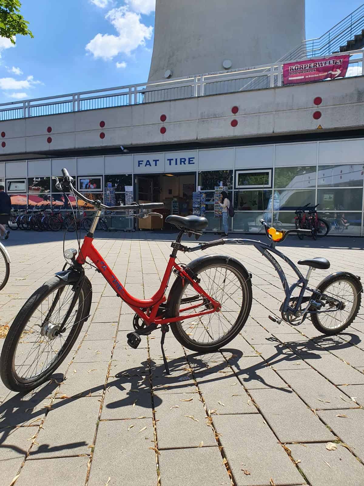A red bicycle with a single-wheeled tandem attached