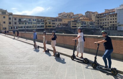 A group on e-scooters pauses for a photo on a bridge in Florence, Italy