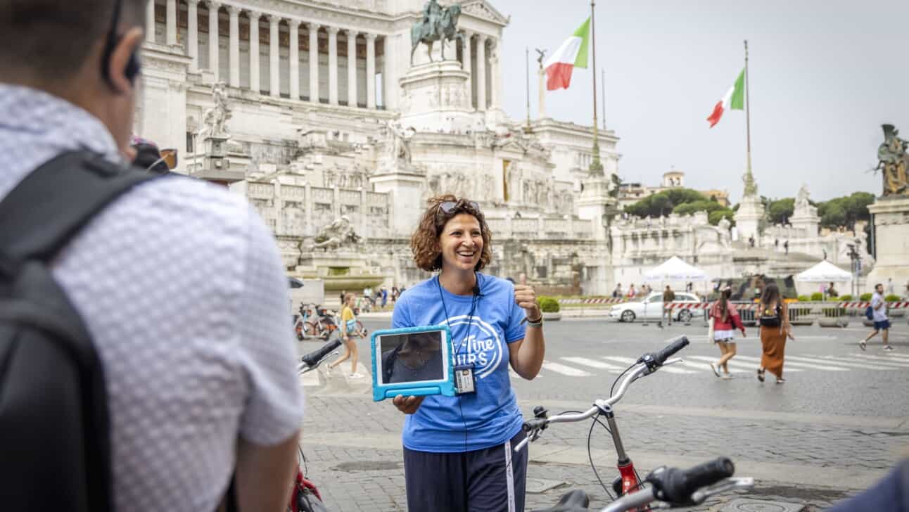 A guide smiles while explaining the history of the Vittorio Emanuele II monument in Rome, Italy