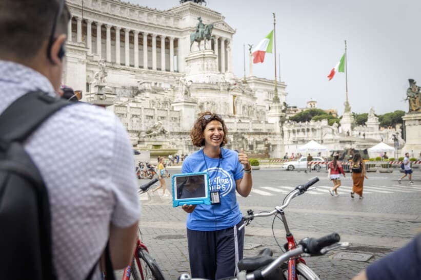 A guide smiles while explaining the history of the Vittorio Emanuele II monument in Rome, Italy