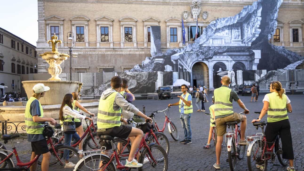 A group of cyclists stops near the French Embassy in Piazza Farnese in Rome, Italy