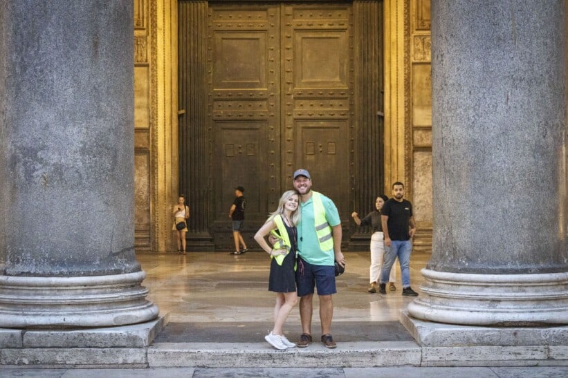 A couple poses for a photo in between the columns of the Pantheon in Rome, Italy