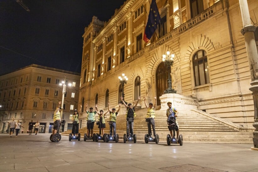 A group on Segways poses for a photo in front of the Italian Parliament Building.