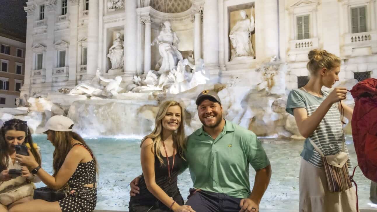 A couple poses for a photo in front of the Trevi fountain