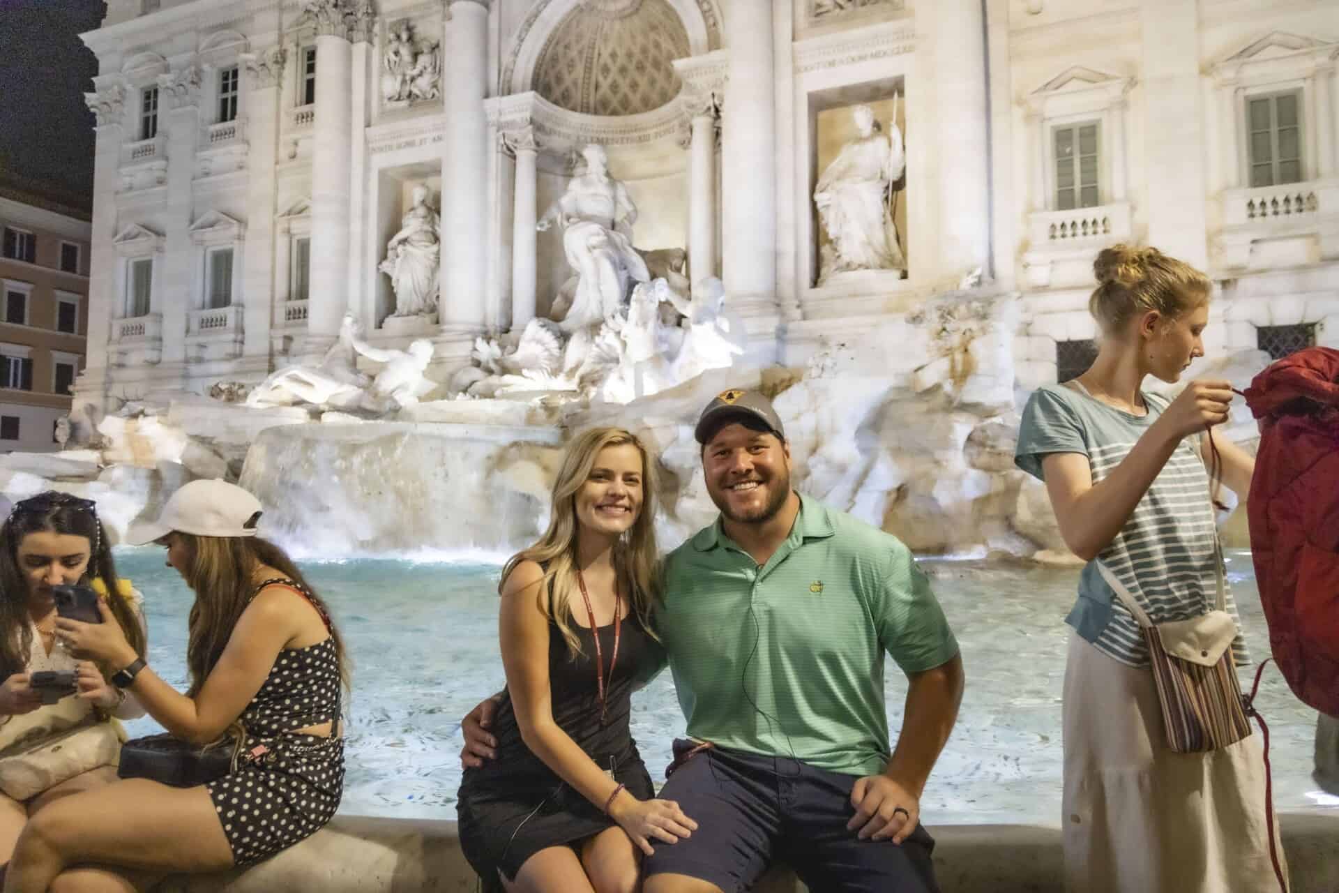 A couple poses for a photo in front of the Trevi fountain