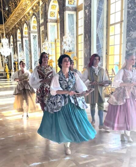 Dancers dressed in period costumes perform inside the palace of Versailles