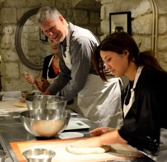 An instructor shows the group how to properly roll out the dough to form a baguette