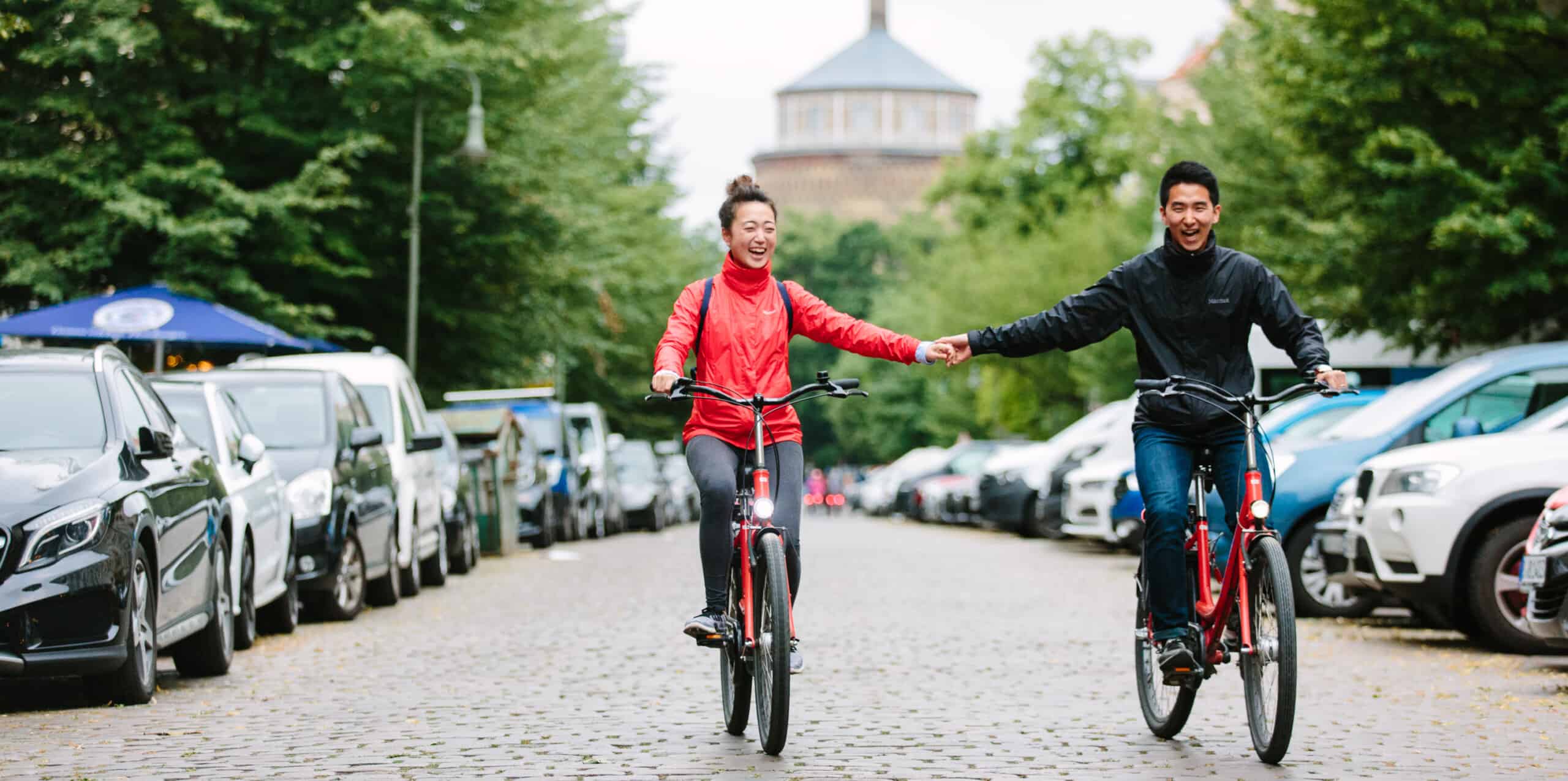 A couple holds hands while riding through Prenzlauer Berg, Berlin, Germany