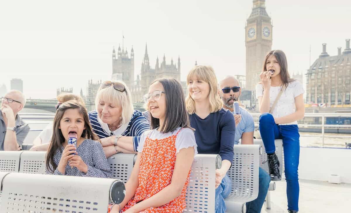 A family enjoys ice cream while on a River Thames Cruise with Big Ben in the background