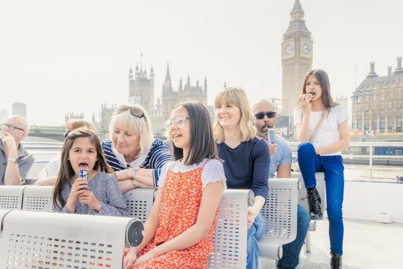 A family enjoys ice cream while on a River Thames Cruise with Big Ben in the background