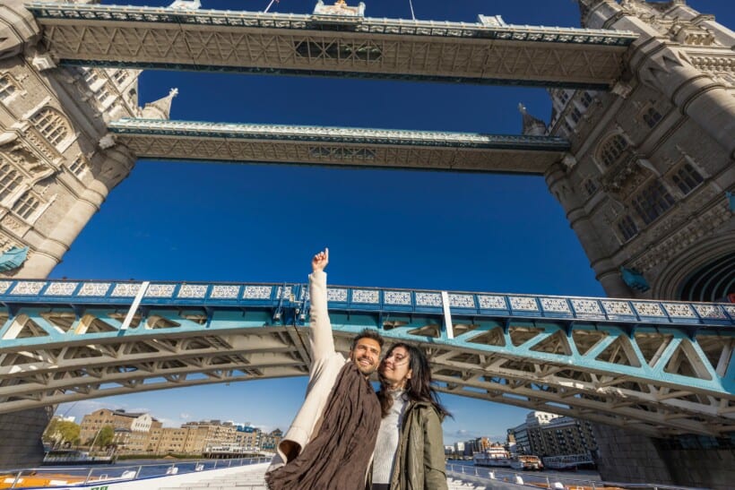 A couple cruises under the Tower Bridge in London