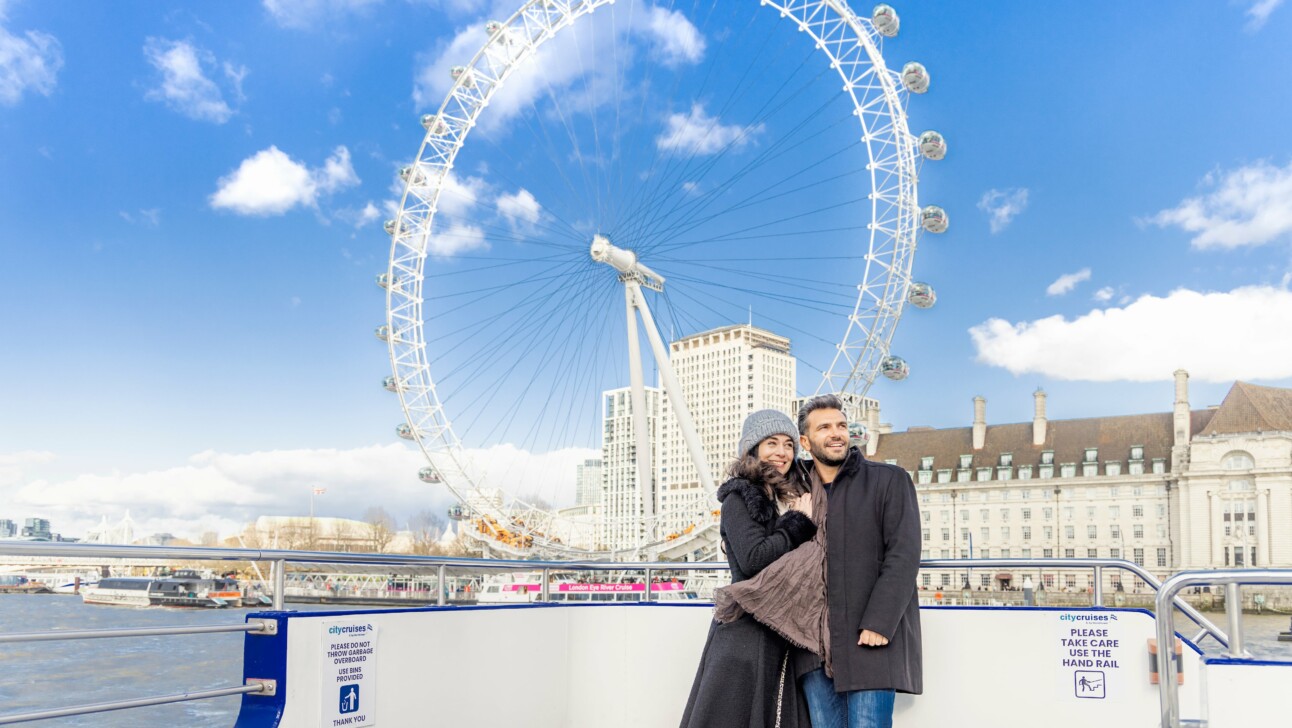 A couple poses for a photo in front of the London Eye