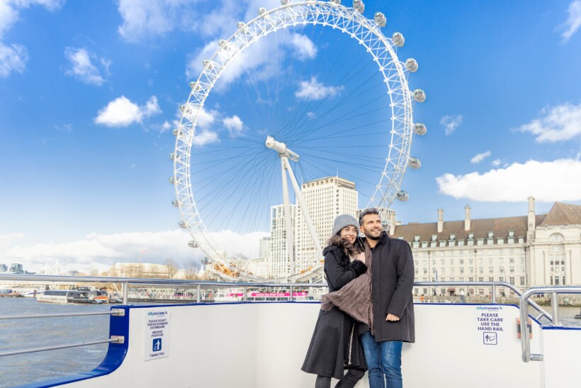 A couple poses for a photo in front of the London Eye