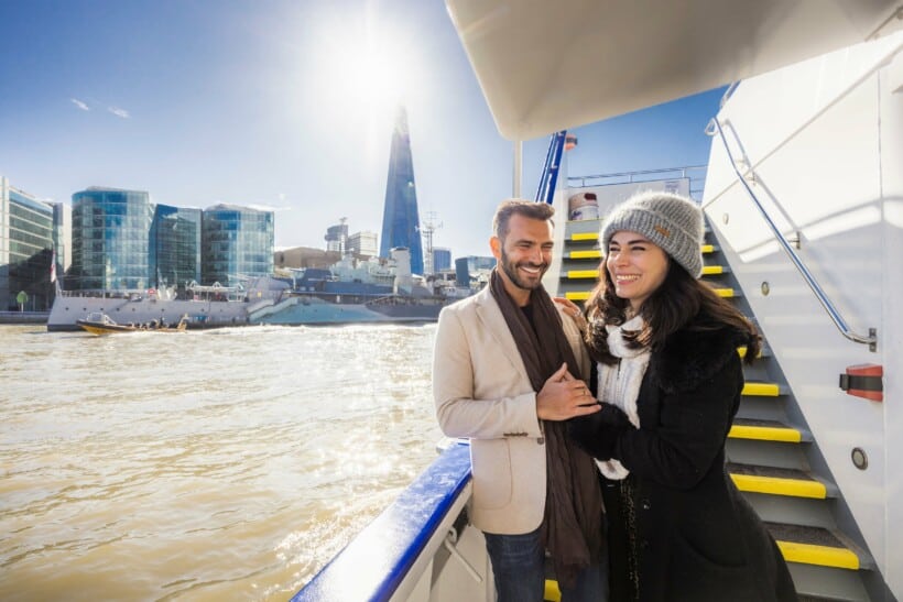 A couple enjoys the views of London from a boat on the River Thames
