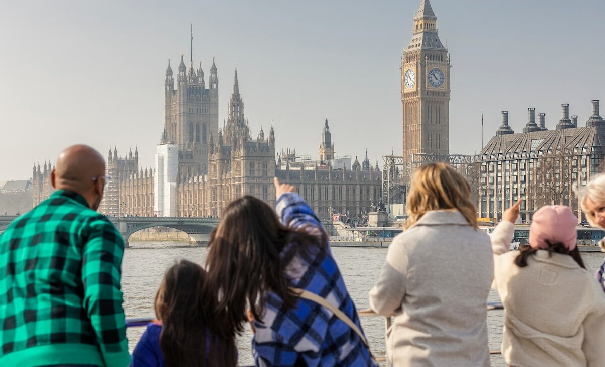 A family admires Parliament and Big Ben from the River Thames in London