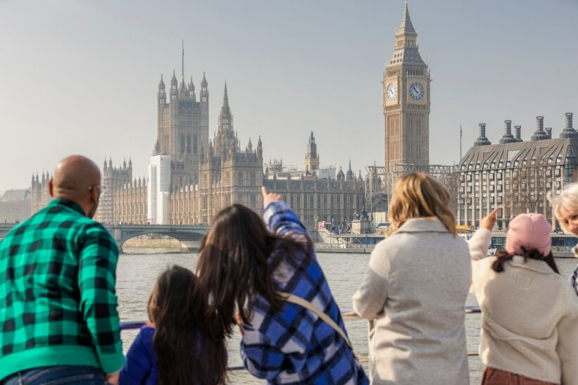 A family admires Parliament and Big Ben from the River Thames in London