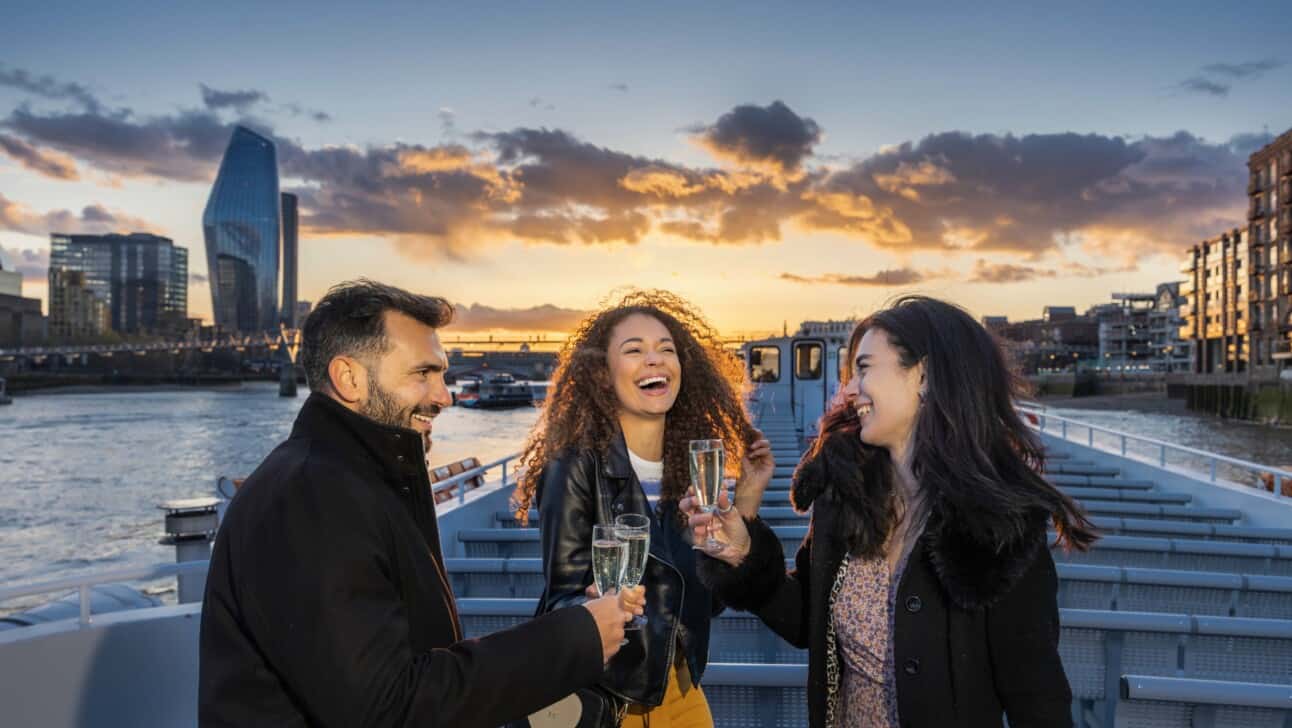 Friends enjoy champagne as the sunsets over the River Thames in London