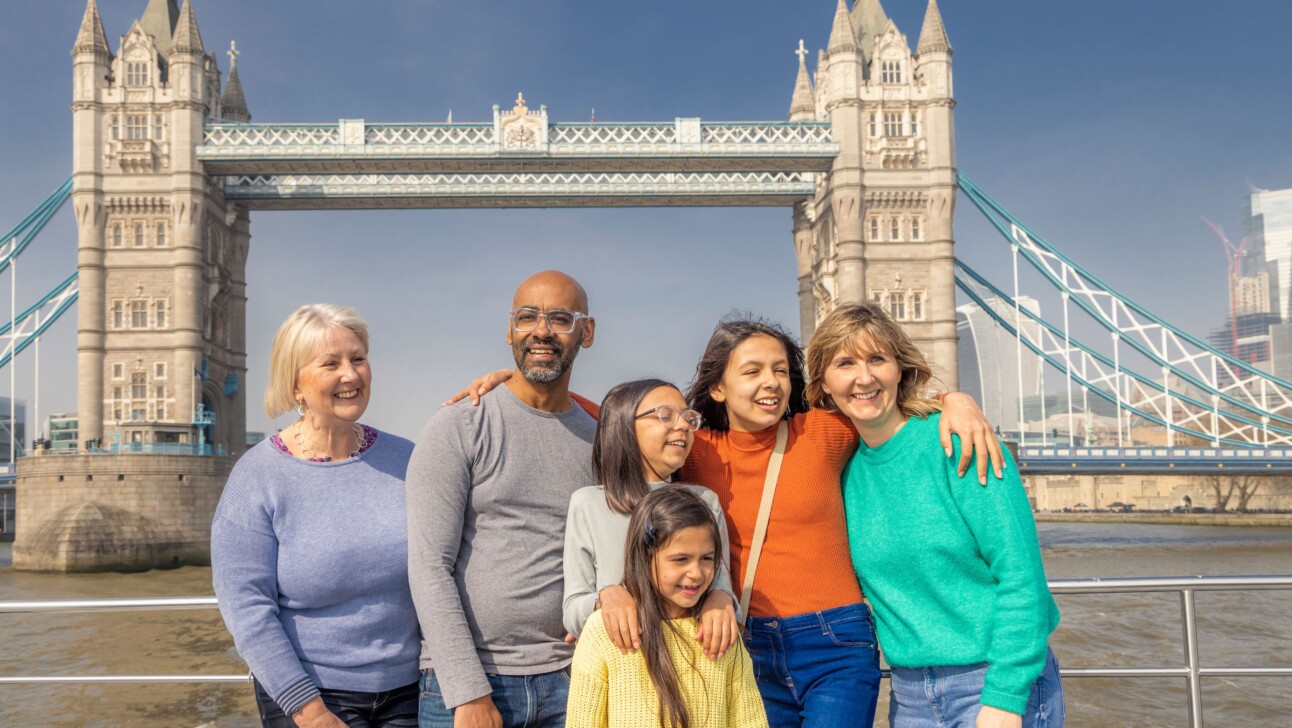 A family poses for a photo in front of the Tower Bridge in London