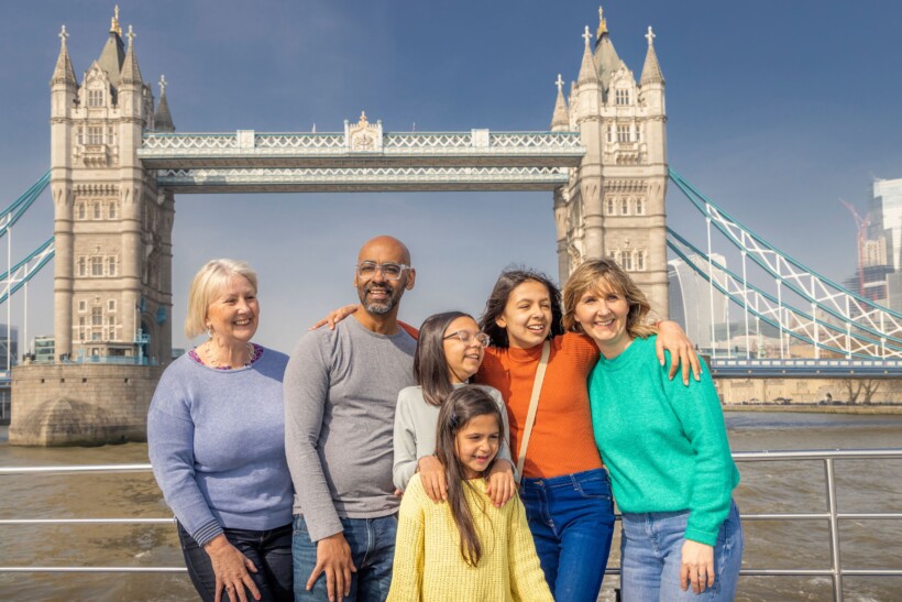 A family poses for a photo in front of the Tower Bridge in London