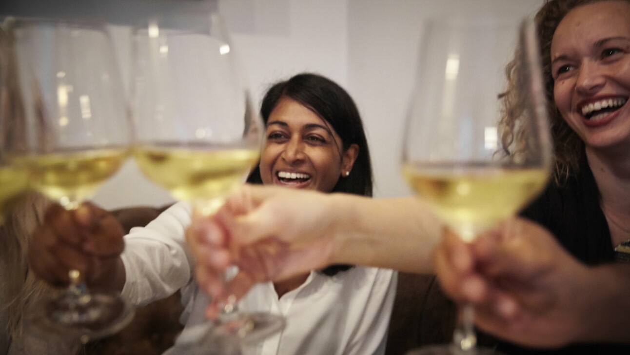 Women smiling cheers their wine glasses together
