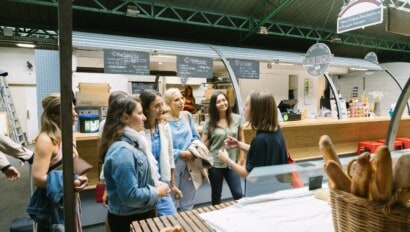 A group of women learn about the various vendors at the market in Paris, France