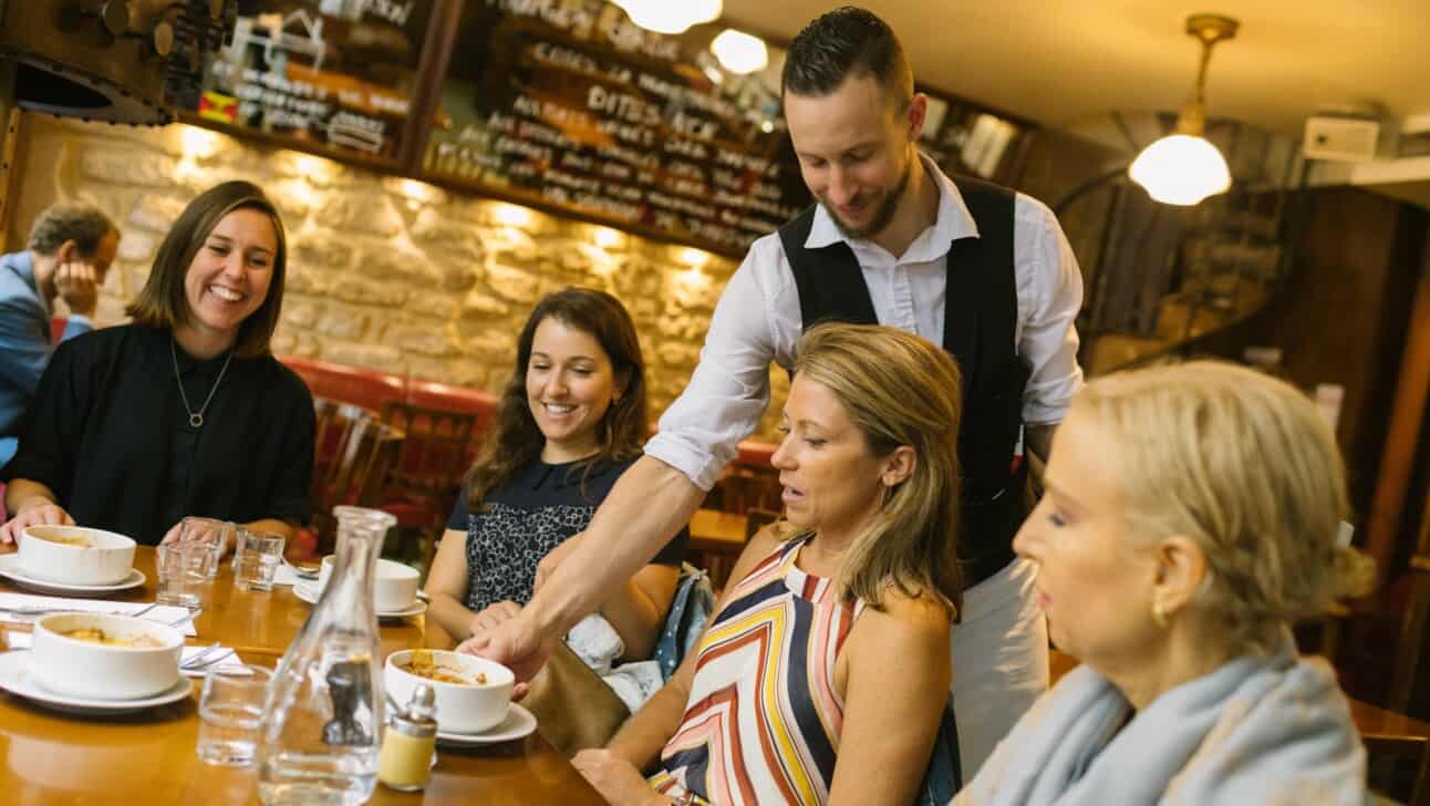 A waiter serves crème brulée to a table of women
