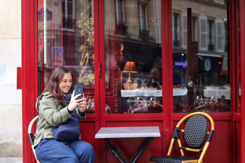 A women takes a selfie at a café frequented by Emily from Emily in Paris