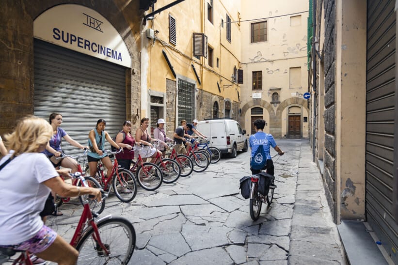 A group of cyclists lines up along a wall before departing on a tour in Florence, Italy