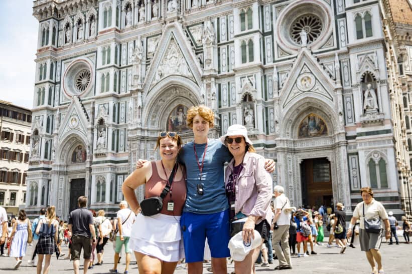 A group of 3 friends pose for a photo in front of the Duomo in Florence, Italy