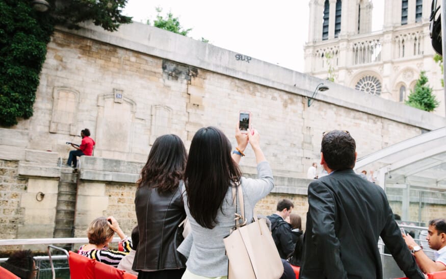 People taking pictures of Notre Dame from a boat on the Seine