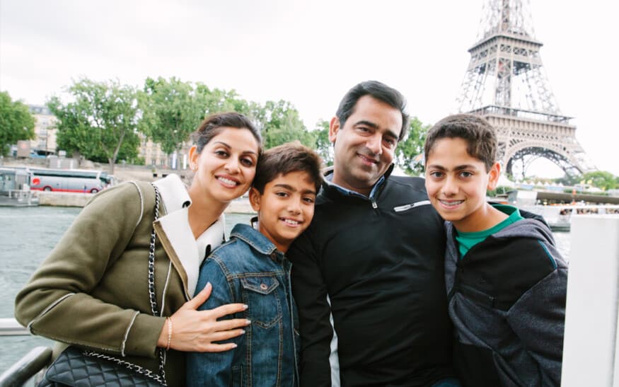 A family poses for a photo on a boat in front of the Eiffel Tower