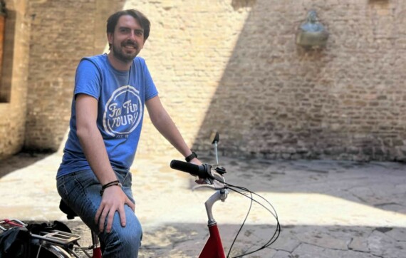 A male in a blue t-shirt on a red bike in Florence, Italy.