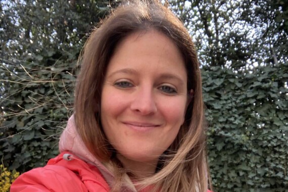 A smiling woman in a red jacket.