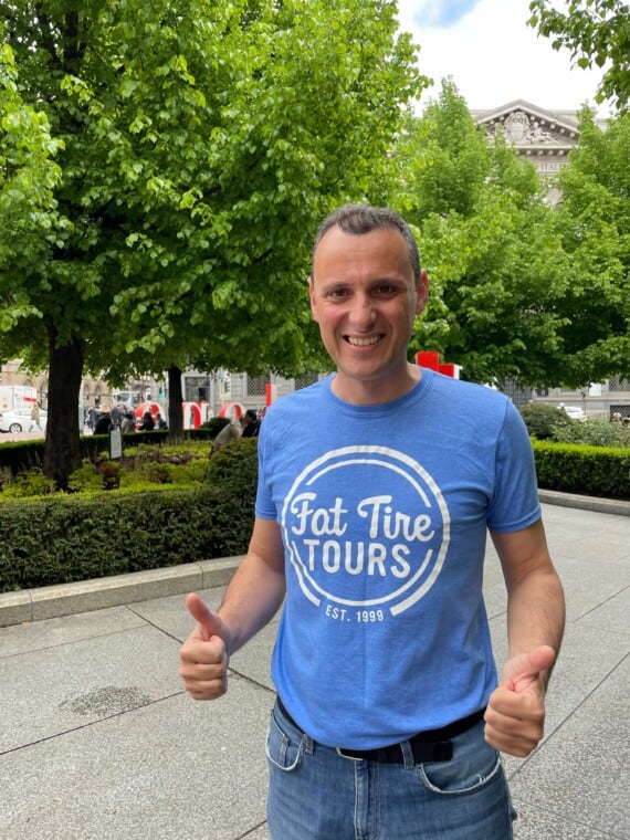 A tour guide in a blue t-shirt gives 2 thumbs up.