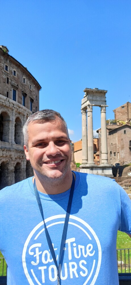 A smiling tour guide in a blue t-shirt