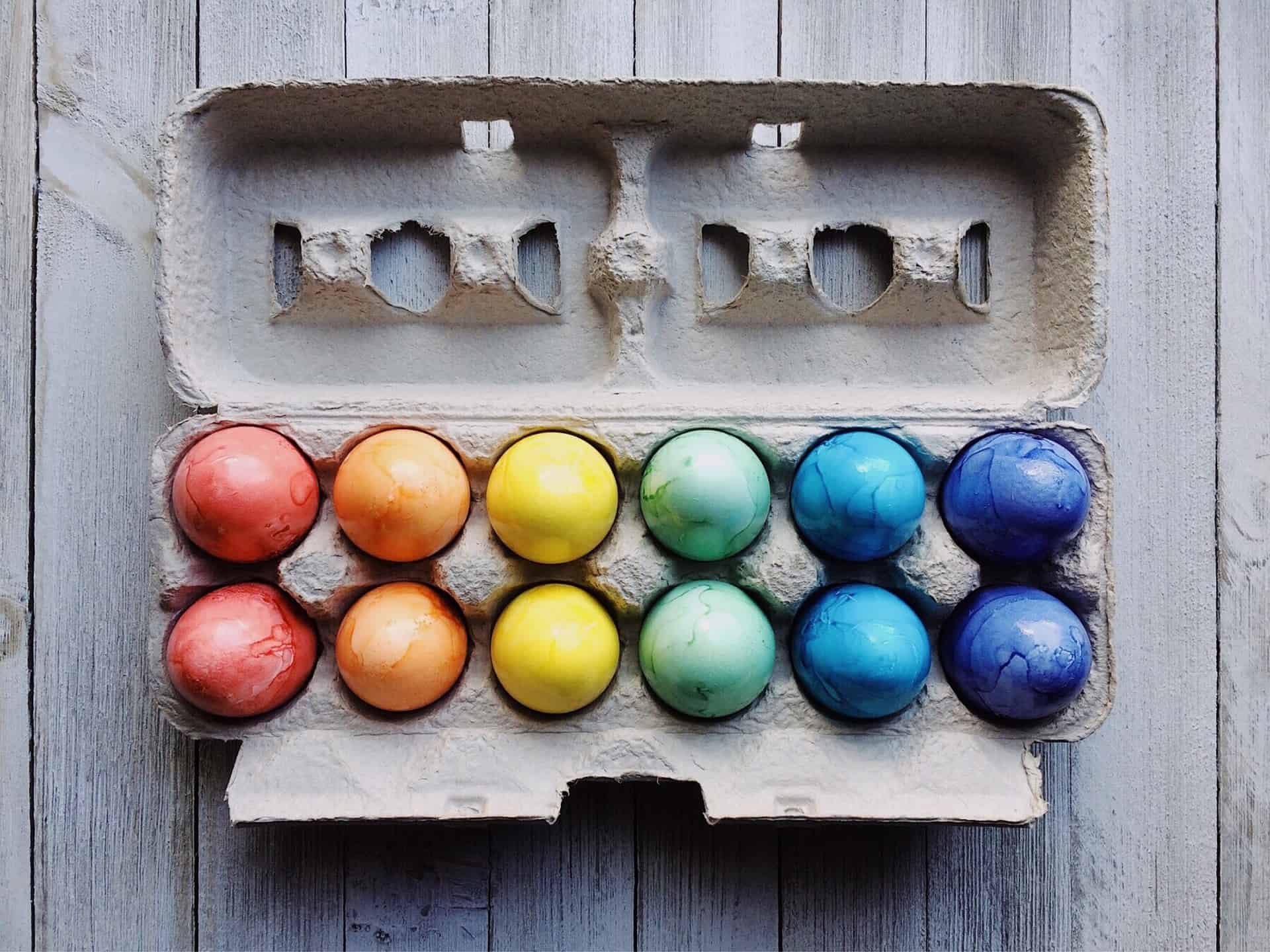 A dozen colorful Easter eggs in an egg container.
