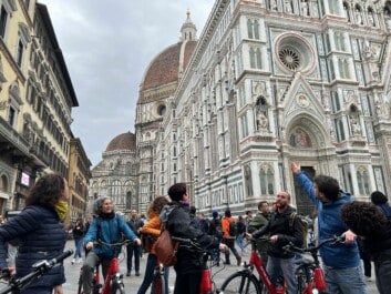 A group of cyclists stop at the Duomo in Florence Italy to learn about it from their tour guide