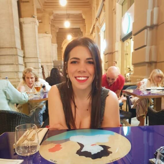 A woman smiling while leaning forward at a table