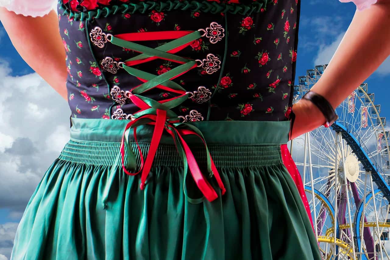 A woman ties on her traditional German clothing with a ferris wheel in the background