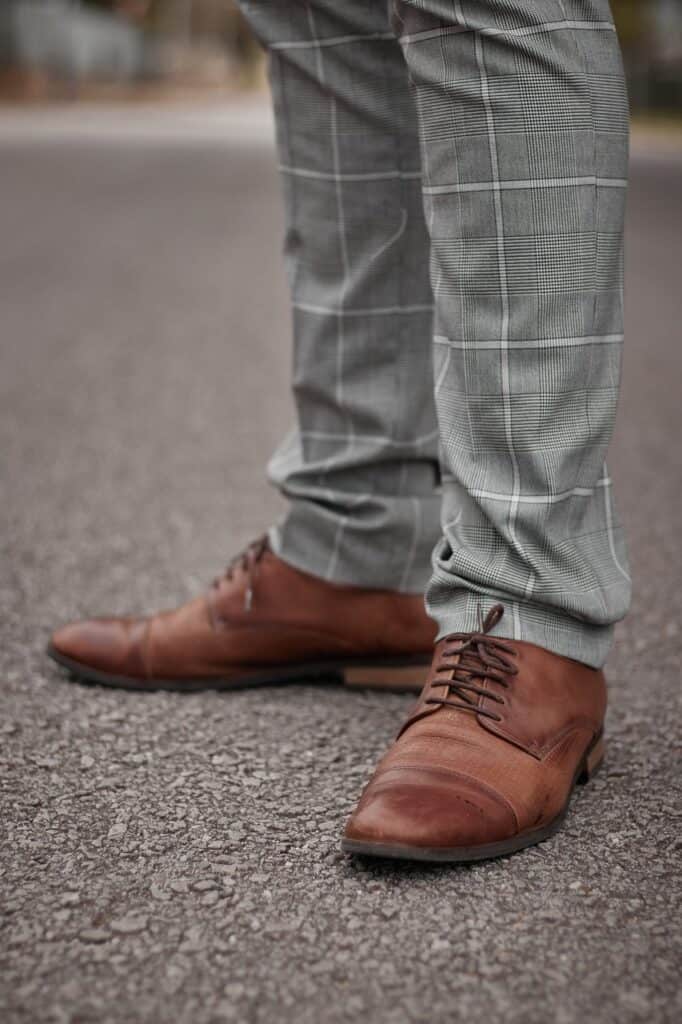 A gray, patterned pair of trousers and brown dress shoes