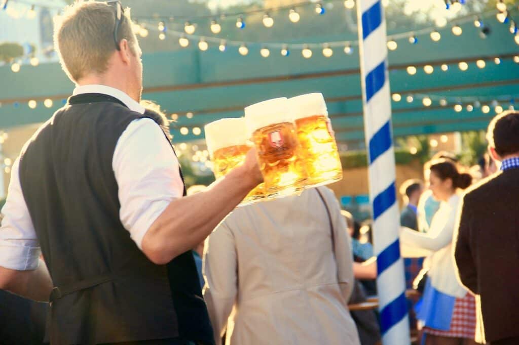 A man wearing traditional German clothes carries beer at Oktoberfest