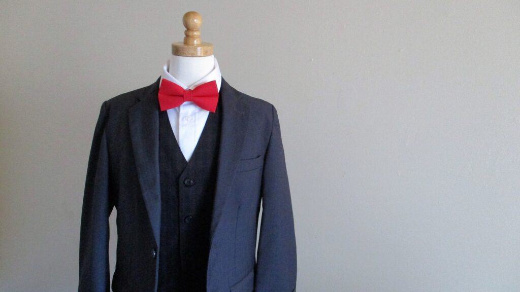 A navy blue suit with a white shirt and red bow-tie on a mannequin