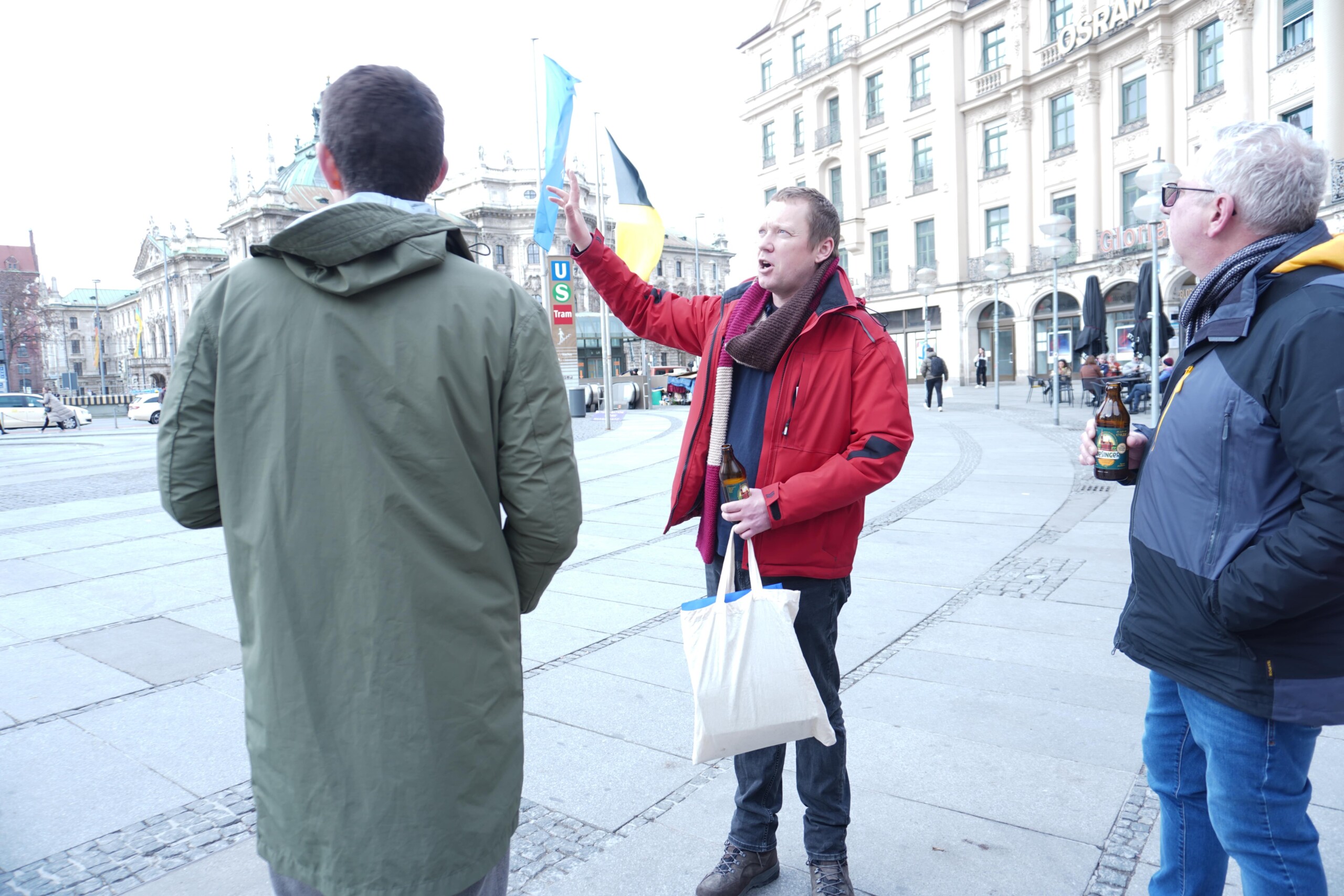 A tour guide in a red jacket describing the surroundings in Munich