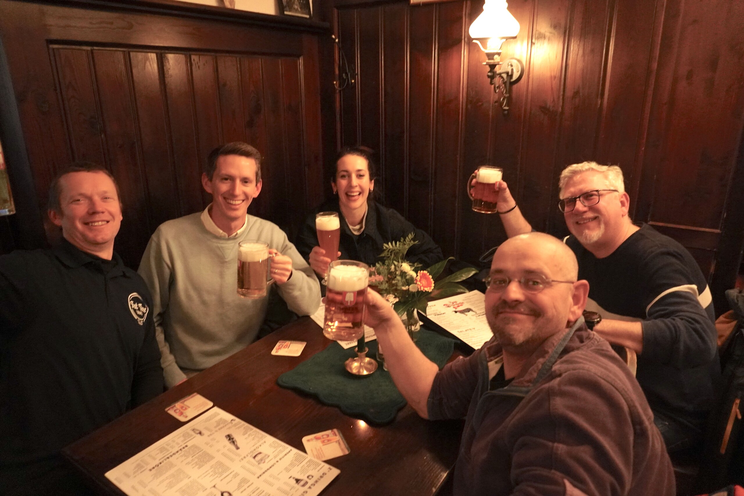 A group of five hold up their drinks at a beer hall in Munich