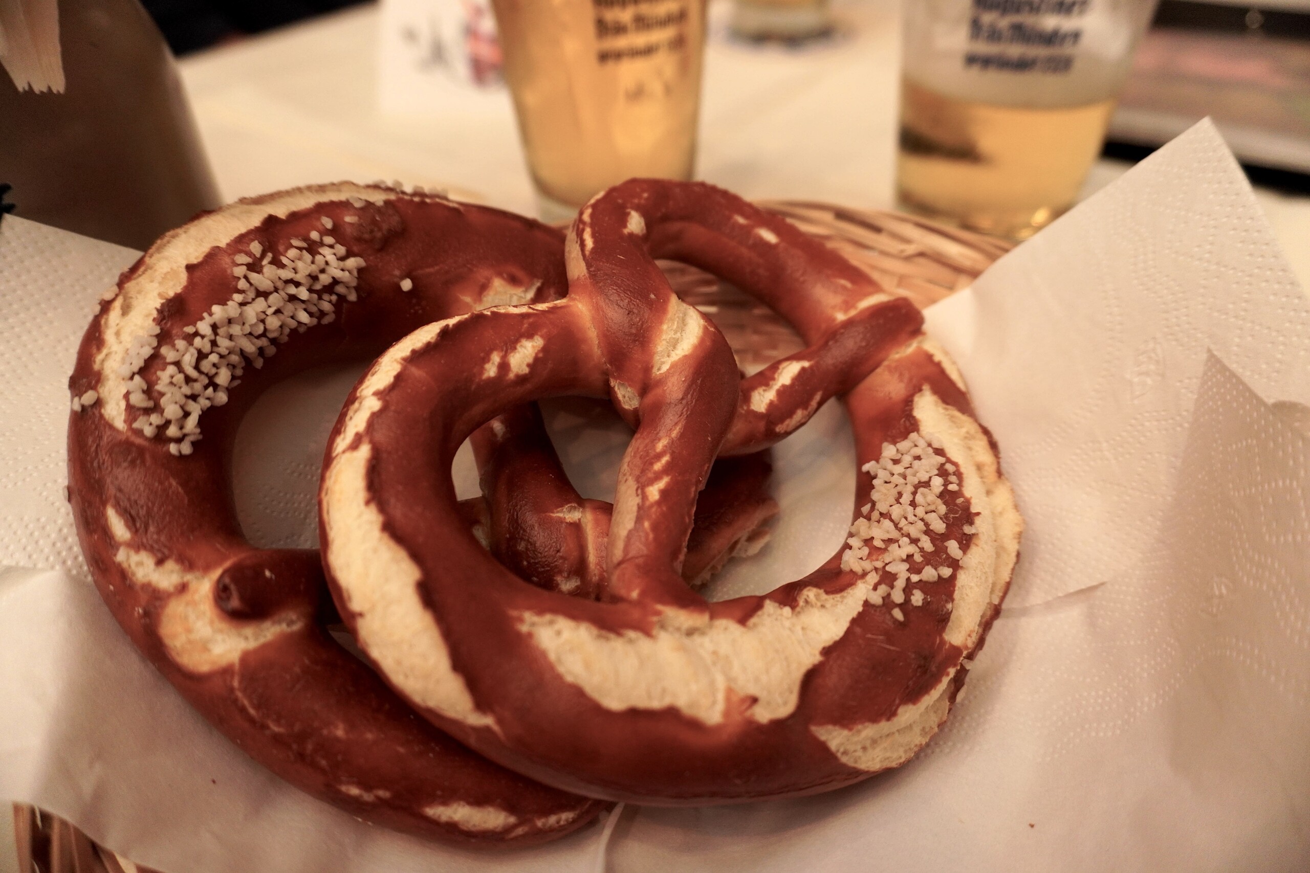 Two soft pretzels with beer in the background