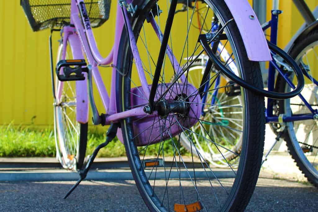 A purple bike is propped up outside on the pavement 