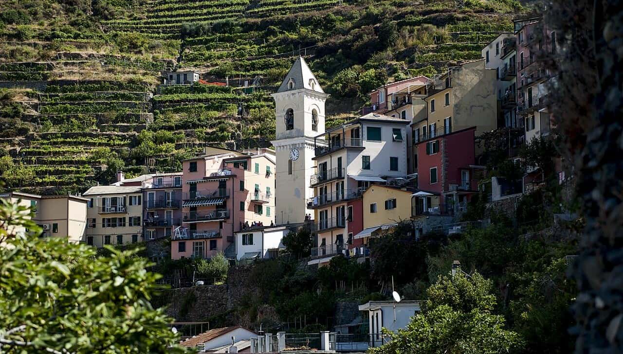 A church steeple and colorful houses along a steep hill in Italy