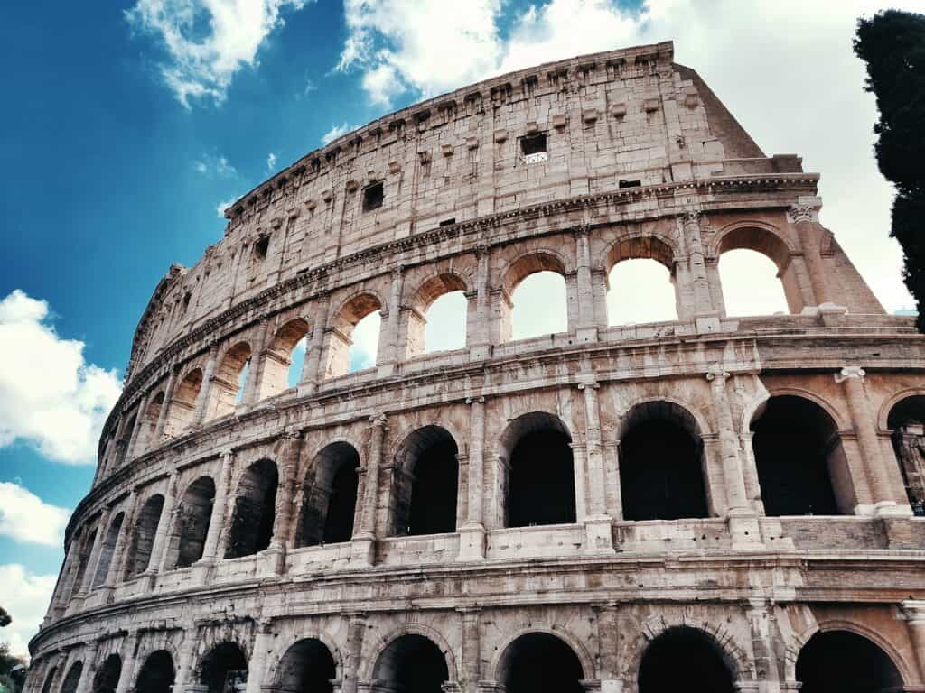The Colosseum in Rome is pictured with the backdrop of a blue sky and white clouds